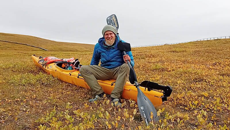 kayaker in yellowish field sitting on kayak