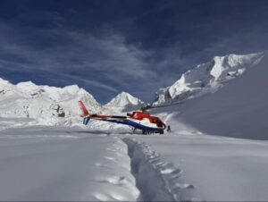 A helicopter on a snowy plain loaded with fresh snow.