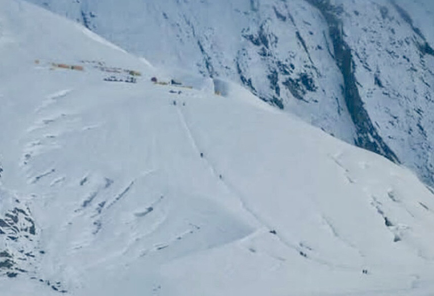 tiny dots of climbers on snowy mountain