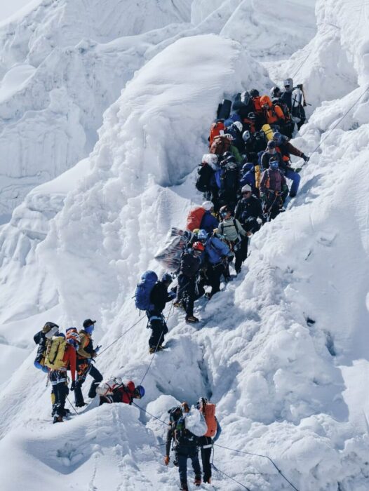 Climbers jammed among seracs, all clipped to a fixed rope.