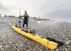 kayaker stands by kayak on arctic beach
