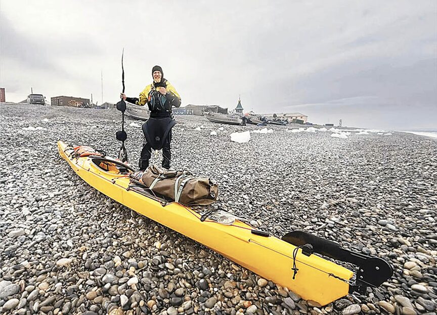 kayaker stands by kayak on arctic beach