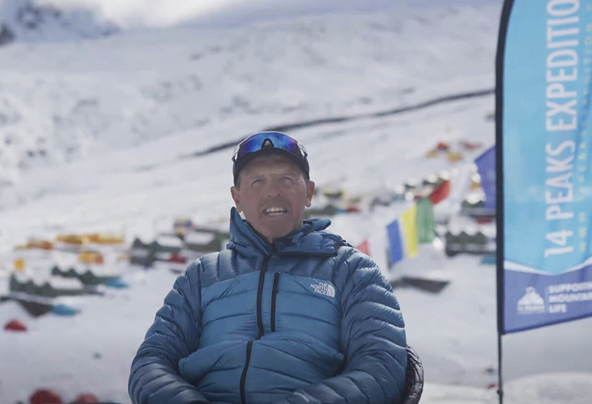 guy in blue parka sitting in base camp
