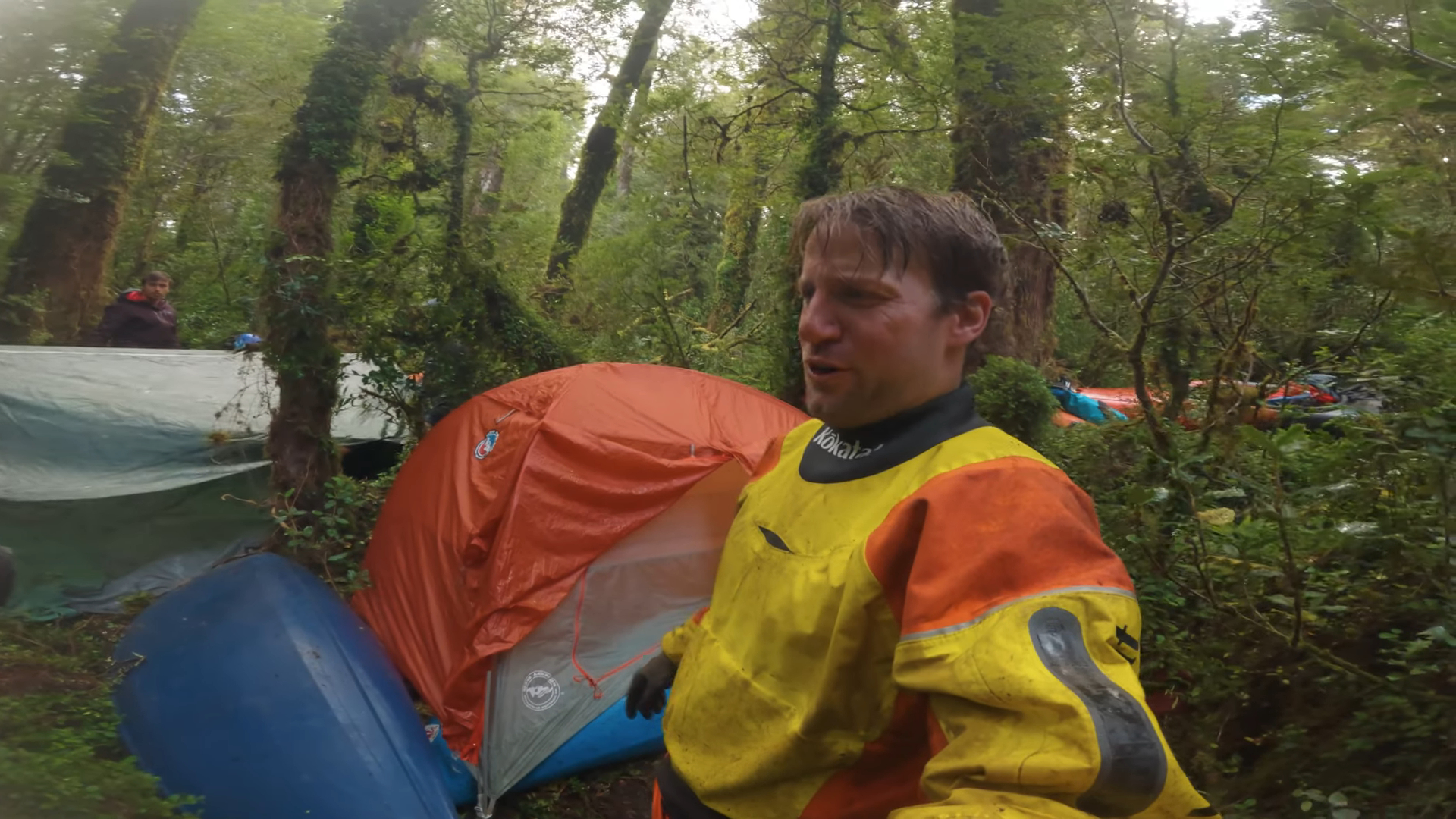 A man standing in front of a tent in the dense jungle