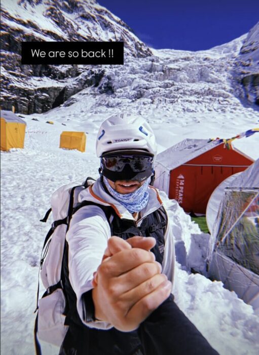 Climbers shake hands in a snowy base camp in a sunny day. 