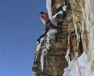 A climber on an overhanging rock section of a mixed route.