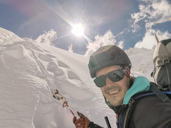 A climber bealying himself on a snow ramp.