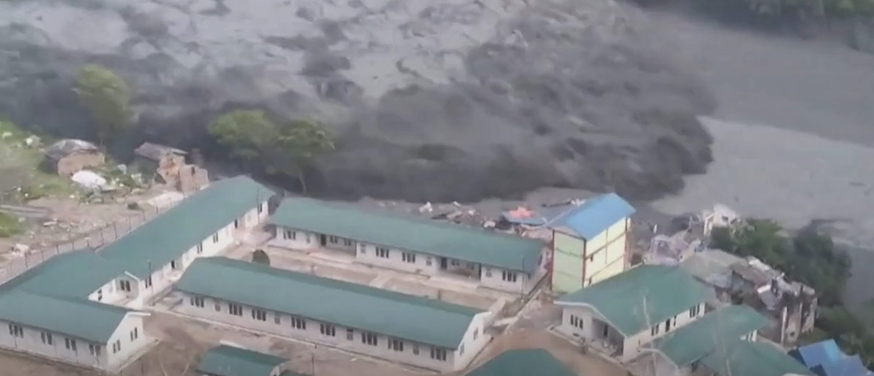 A flooded river sweeps through some houses in Nepal.