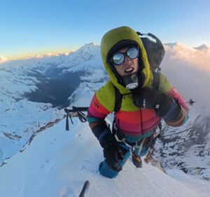A climber on a spiky snow summit takes a selfie.