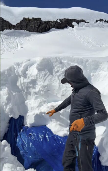 A sherpa with a shovel after uncivering a tent buried in meters of snow. 