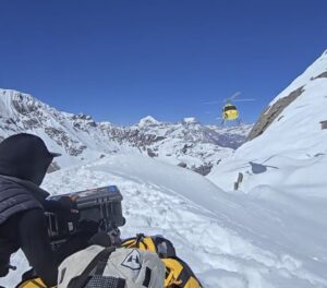 A Nepalese rescuer waits on the snow for a helicopter to arrive.