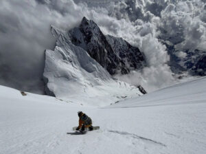 A rider snowboards down a steep Himalayan face.