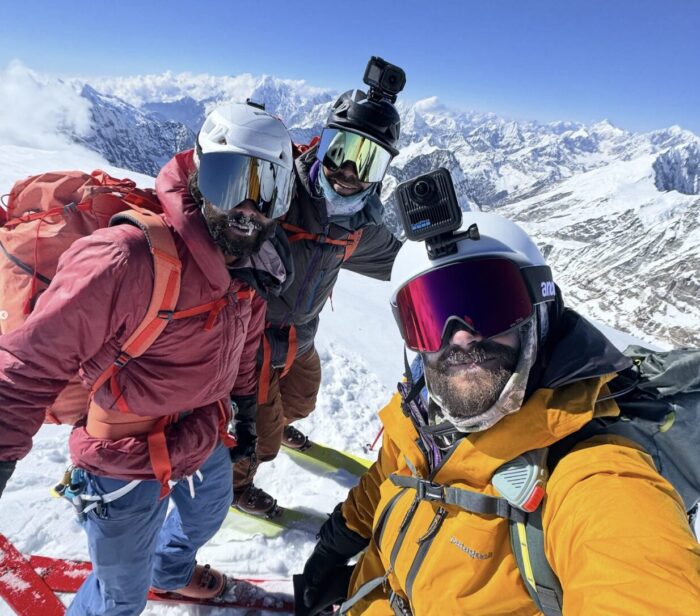 Three skiers take a selfie on a Himalayan summit. 