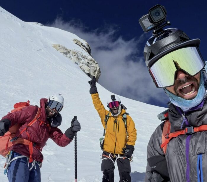 Three skiers on a Himalayan peak. 