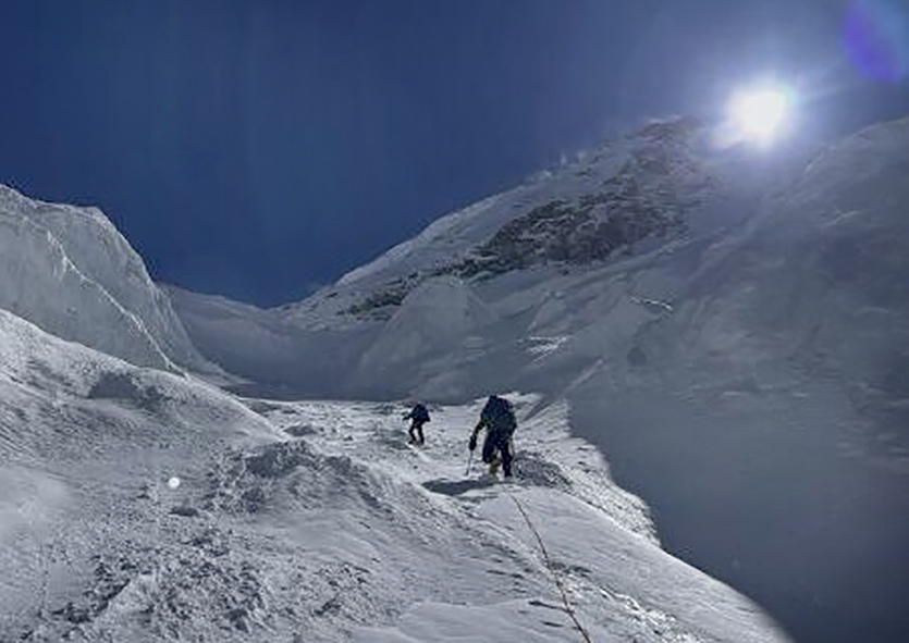 Two climbers going up among crevasses covered in fresh snow.