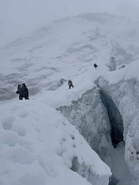 Climbers among seracts covered in fresh snow, in a foggy day. 