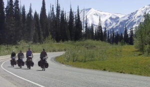 Four cyclists in a forest, mountains in background