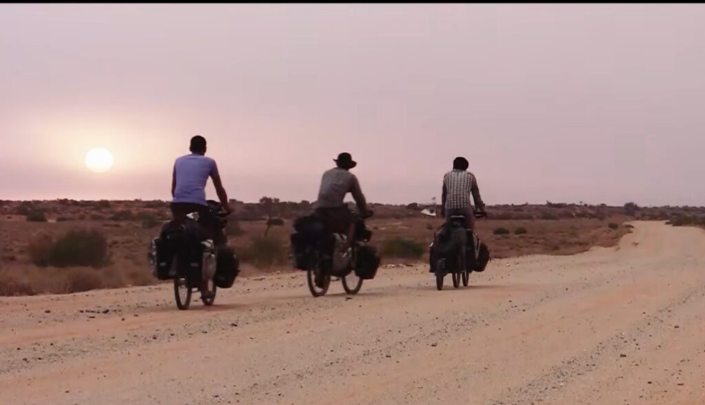 Three men biking through the outback at dusk