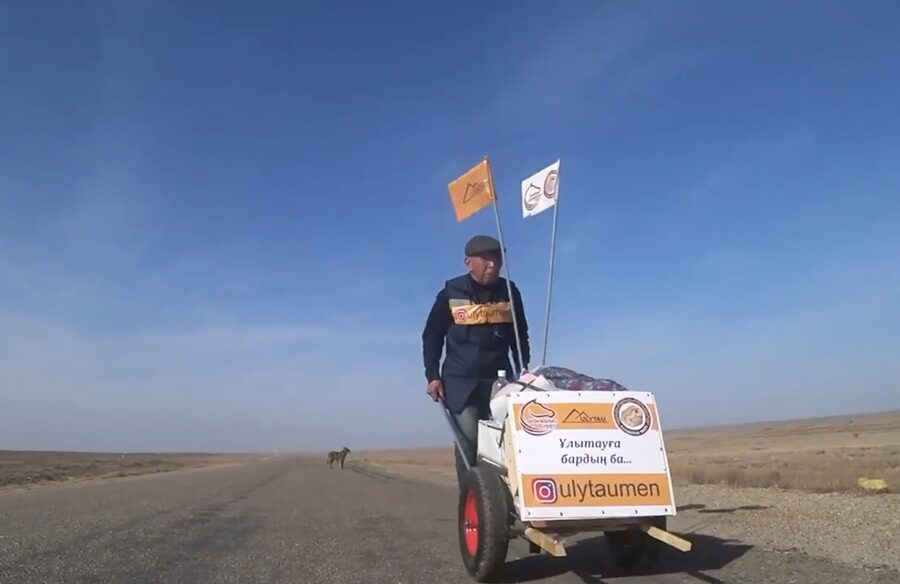 man pushing a cart on a lonely dirt road