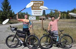 Pete and Carter stading with their bikes and paddles infront of the Canadian Border at the start of their journey. They are bikerafting from Canada to Mexico.