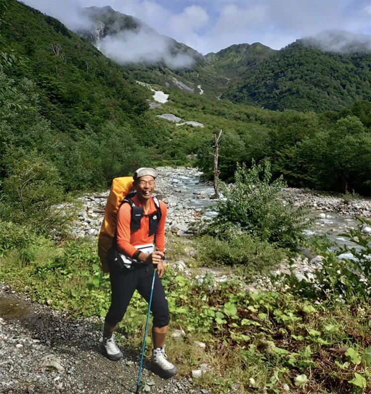 japanese guy smiling while hiking in mountains