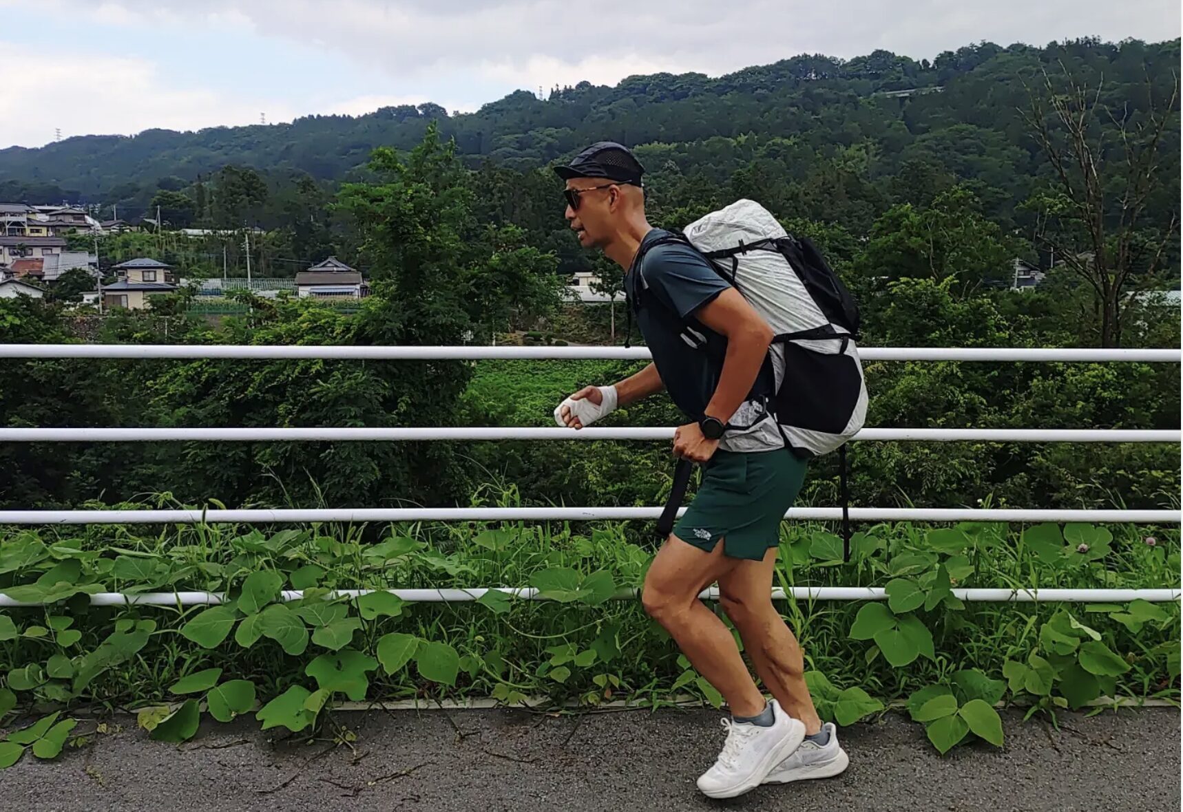 Japanese guy running alohng road with backpack