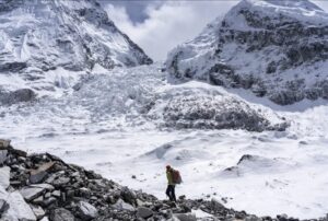 A man on morraine ground with Everest's Khumbu icefall in background.