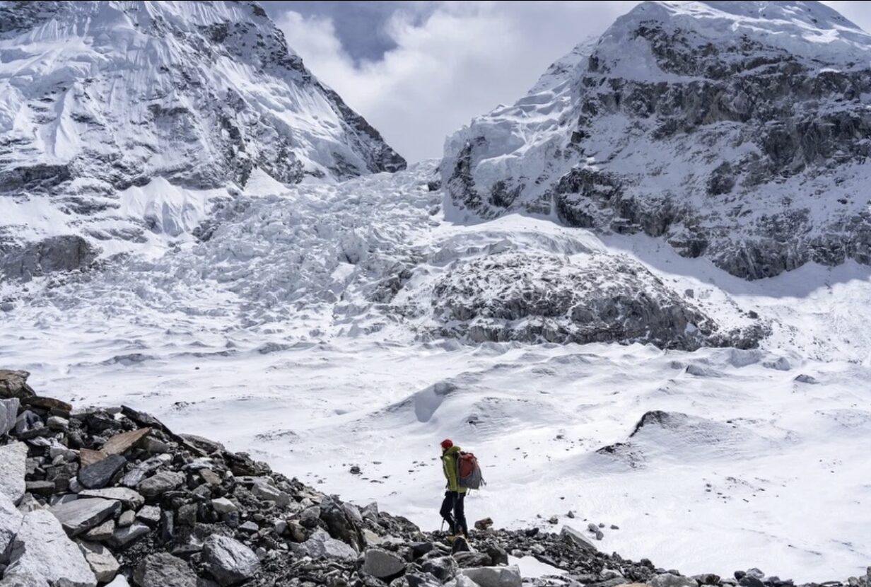 A man on morraine ground with Everest's Khumbu icefall in background.