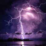 Forked lightning strikes a lake at night